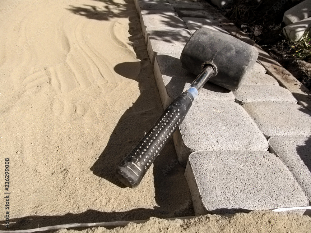 Smooth rows of gray paving slabs on the clean sand and black rubber ...