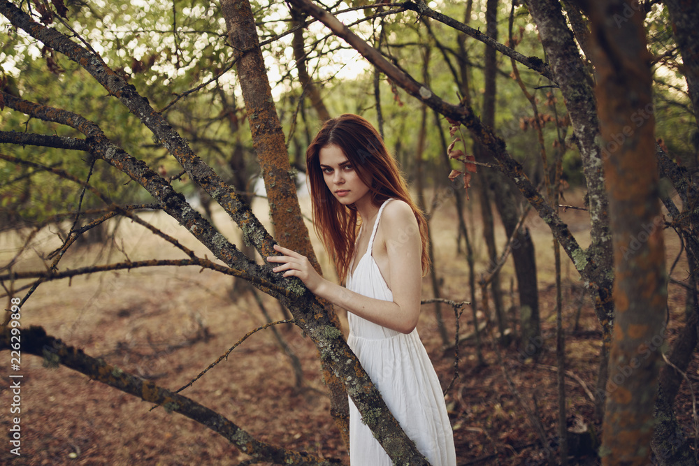 woman stands in the forest leaning on a tree woman stands in the forest leaning on a tree