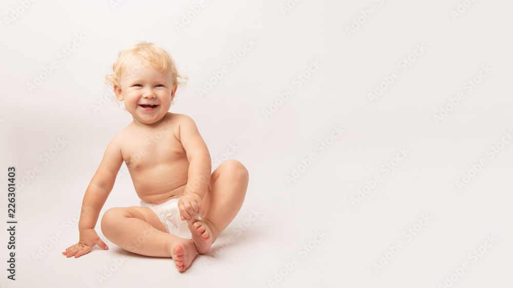 Infant child baby girl in diaper laughs happy looking at the camera isolated on a white background Infant child baby girl in diaper laughs happy looking at the camera isolated on a white background