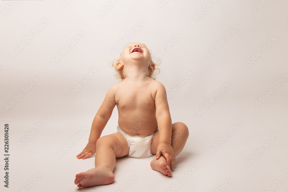 Infant child baby girl in diaper laughs happy looking at the camera isolated on a white background Infant child baby girl in diaper laughs happy looking at the camera isolated on a white background