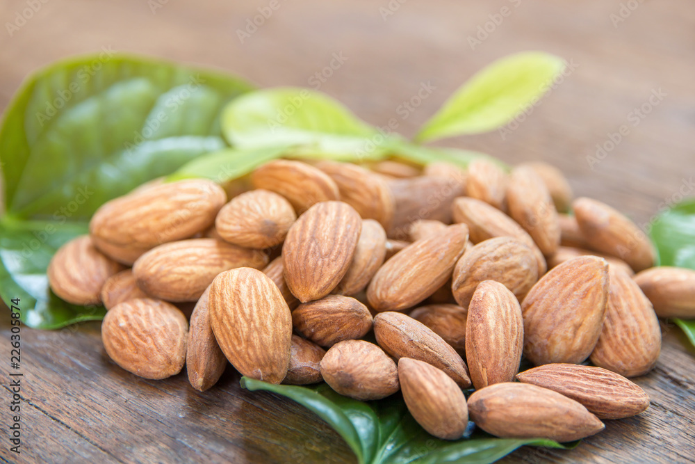 close up of almonds grain roast on wood background with green leaves close up of almonds grain roast on wood background with green leaves
