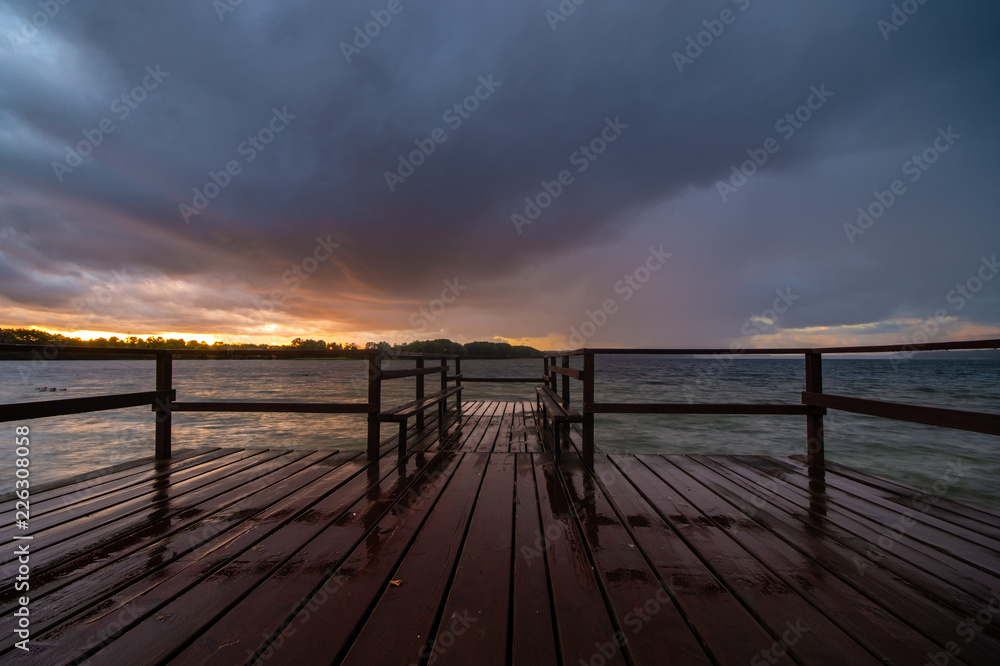 evening storm over the lake, the sky reflecting off the wet planks of the wooden jetty