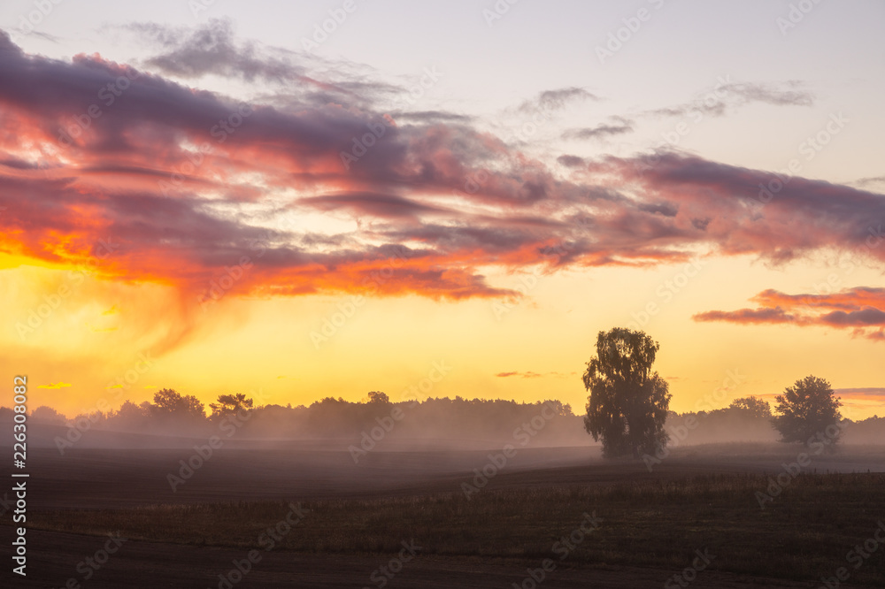 beautiful, dramatic sky over an autumn field enveloped in the morning mists-Poland, Drawskie Lakeland