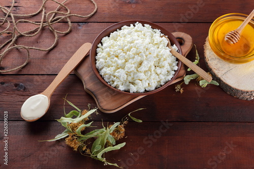 Cottage cheese and cream. Soft cheese and honey on wooden boards. Cottage cheese in pottery and linden flowers. Twine on wooden background. Cream in wooden spoon. Honey on wooden stand. Copy space