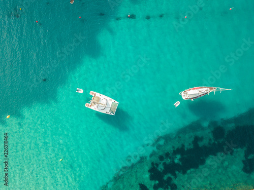 Aerial bird's eye view drone of boat docked in mediterranean tropical beach with turquoise - sapphire waters © Sam Foster