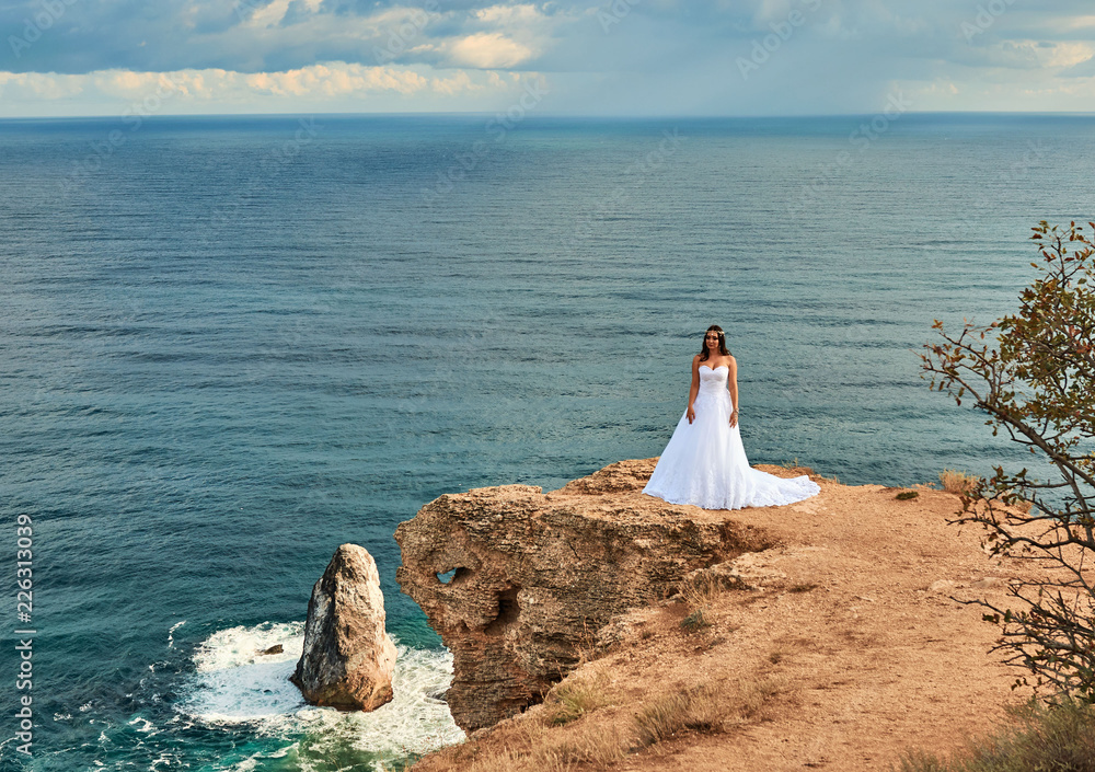 Brunette bride in a long white dress near the sea Brunette bride in a long white dress near the sea