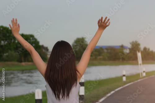 Asian lady spread her hands in the sky to show their happiness and victory with the concept of life and success on the sky in the morning.