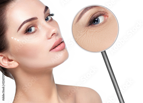 beautiful woman face with lifting arrows on skin and magnifying glass showing aging skin around eyes. Wrinkles around the eyes, the procedure for rejuvenating dry and aging facial skin, mesotherapy
