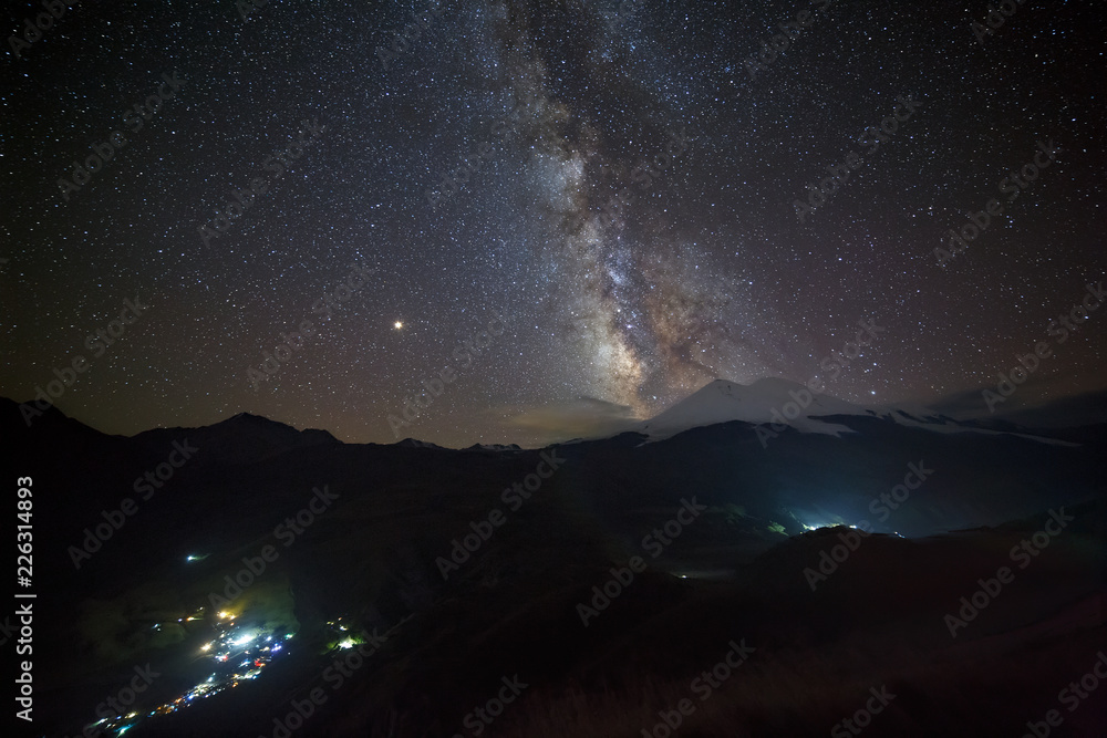 Stars of the Milky Way at night in the sky above Mount Elbrus. View of the northern slope of the two peaks of the stratovolcano. The highest peak of Russia and Europe is 5642m.