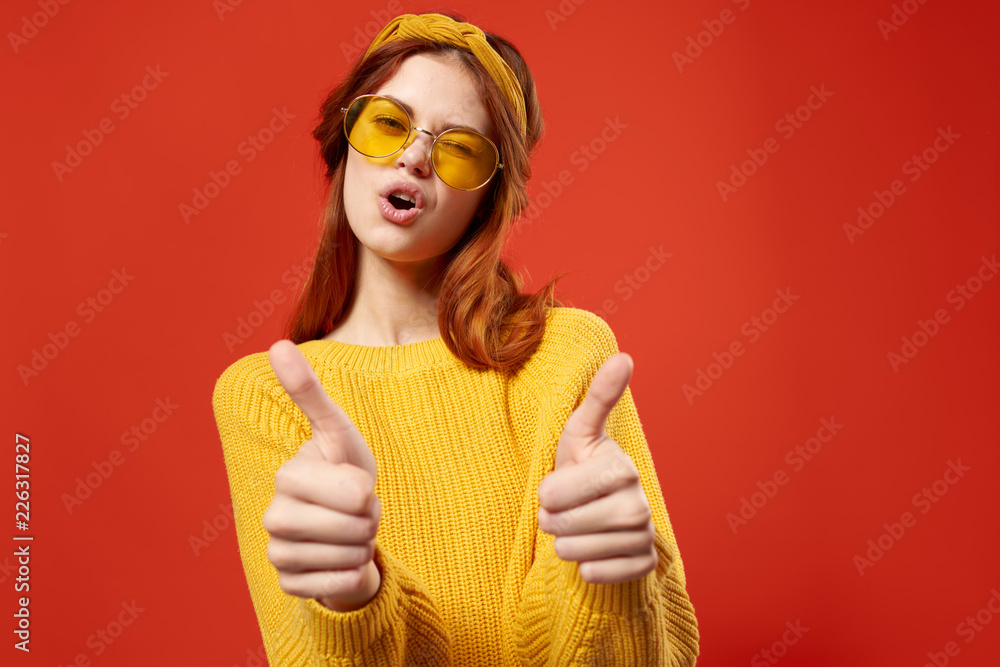 woman in yellow sweater and glasses shows thumb approving gesture woman in yellow sweater and glasses shows thumb approving gesture