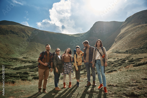 Six friends. Six active people standing with beautiful mountains on the background and looking ready for the journey