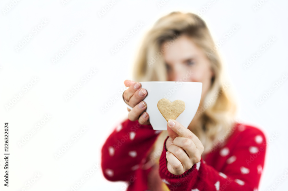 Gentle beautiful girl hands hold bright tasty sweet Christmas heart-shaped cookies with a mug of tea on a white background Gentle beautiful girl hands hold bright tasty sweet Christmas heart-shaped cookies with a mug of tea on a white background