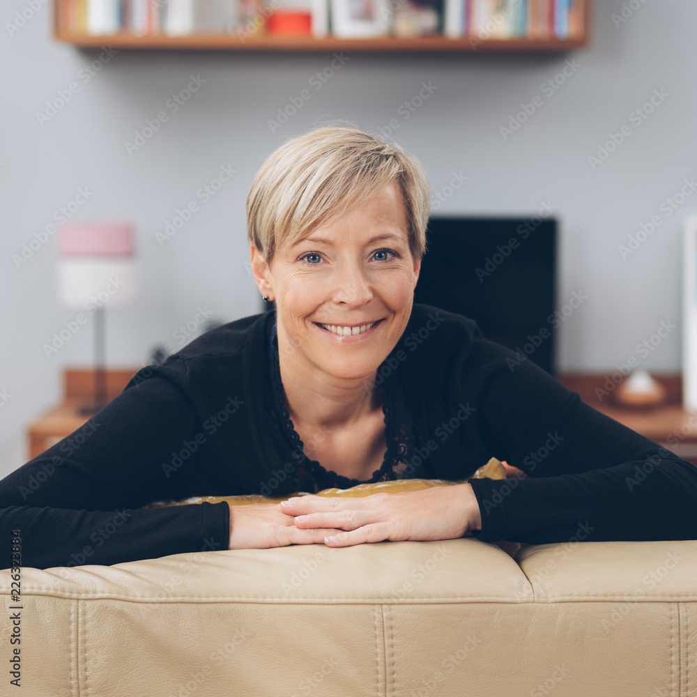 lächelnde ältere frau mit kurzen haaren sitzt auf dem sofa lächelnde ältere frau mit kurzen haaren sitzt auf dem sofa