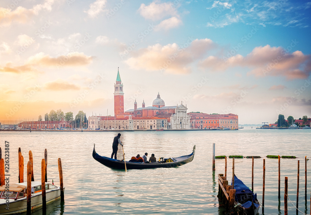 view of lagoon and San Giorgio island in sunrise light with gondolas boats, Venice, Italy