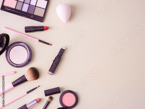 top view of cosmetics concept with lipstick, makeup products, Eyeshadow Palette, powder on cream color table background.
