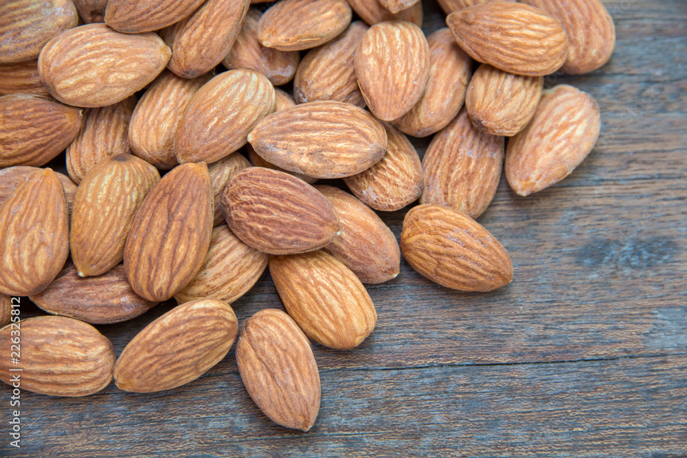 close up of almonds grain roast on wood background with green leaves close up of almonds grain roast on wood background with green leaves