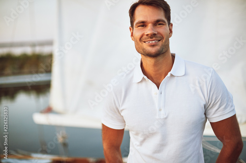 Young man smiling while standing alone on his yacht