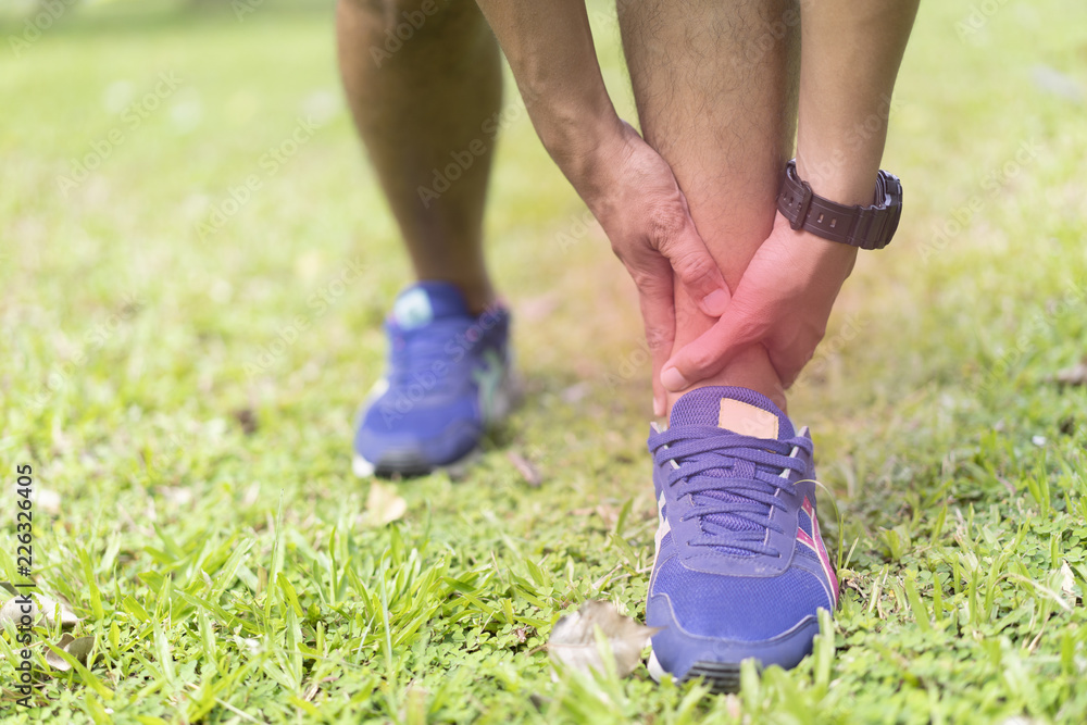 sportman holding his ankle pain while jogging or run in national park. sportman holding his ankle pain while jogging or run in national park.