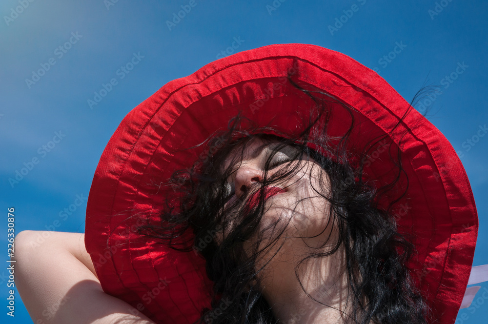 Beautiful woman in red hat enjoying summer sunshine