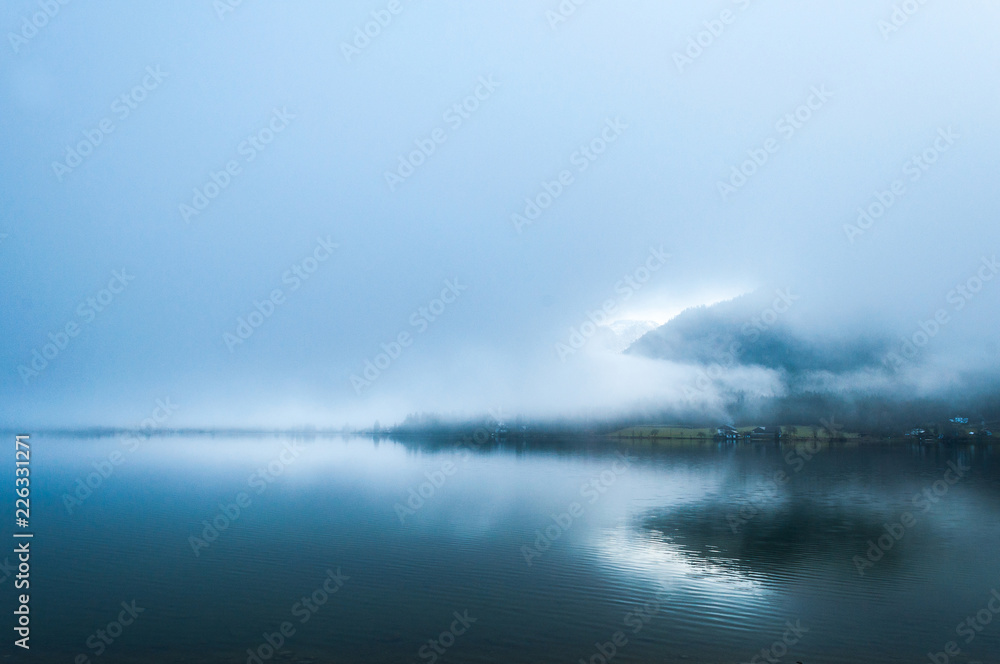 Early foggy  wet morning on the lake between the mountains in Austrian Alps