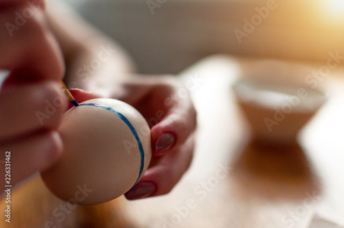 Close shot of hands painting egg in blue