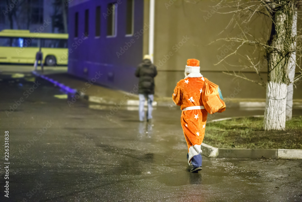 Obraz premium Drunk Santa Claus with a bag of gifts is new year's eve in Russia