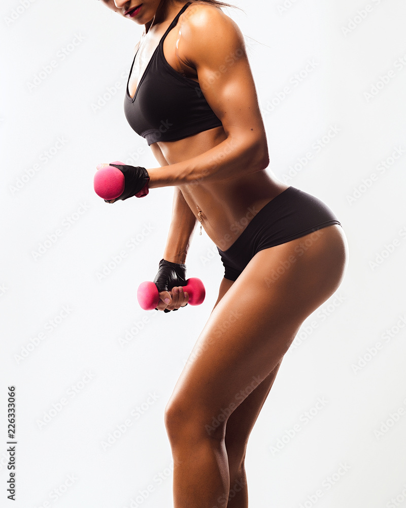 Fototapeta premium Perfect Fitness Body of Beautiful Woman. Fitness Instructor in Sports Clothing. Female Model with Fit Muscular and Slim Body in Sportswear doing Workout. Young Fit Girl Lifting Dumbbells.