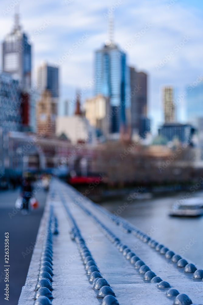 The high rise buildings of Melbourne Australia in the distance from the perspective of Sandridge Bridge over the Yarra River.
