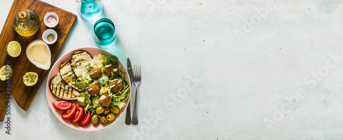 banner of an appetizing dinner or lunch from a salad with tomatoes, grilled eggplants and legume falafel with sesame tahini dressing. Vegan healthy food for the whole family © irynagrygorii