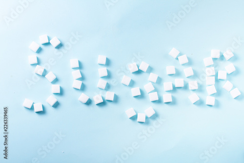 Fototapeta Naklejka Na Ścianę i Meble -  Sugar word in sugar cubes on blue background