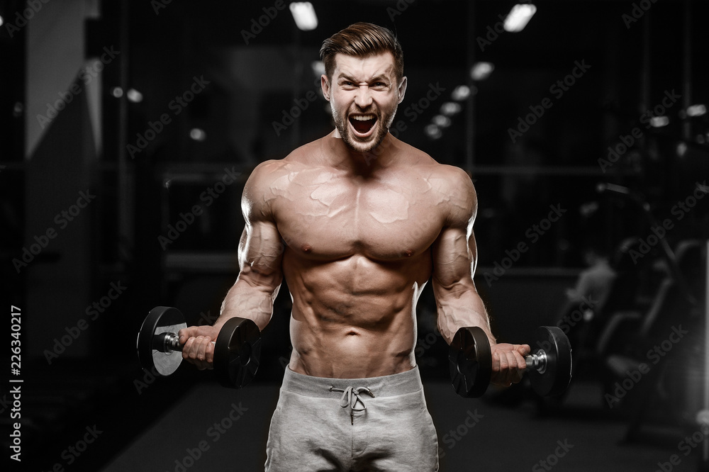 Fototapeta premium sexy strong bodybuilder athletic men pumping up muscles with dumbbells