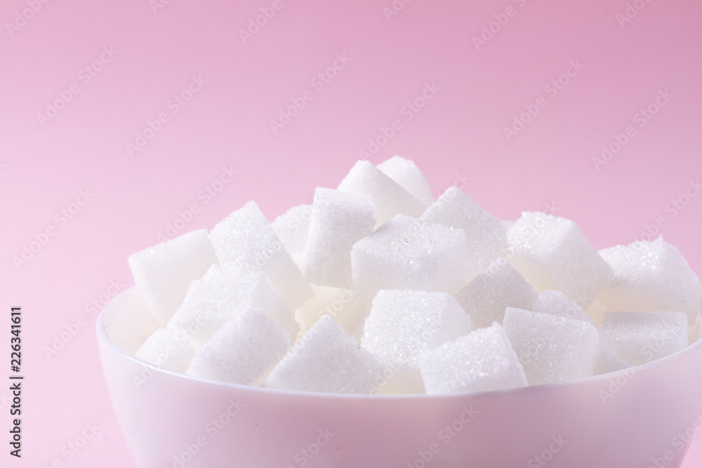 Sugar cubes in white plate on pink background close up Sugar cubes in white plate on pink background close up