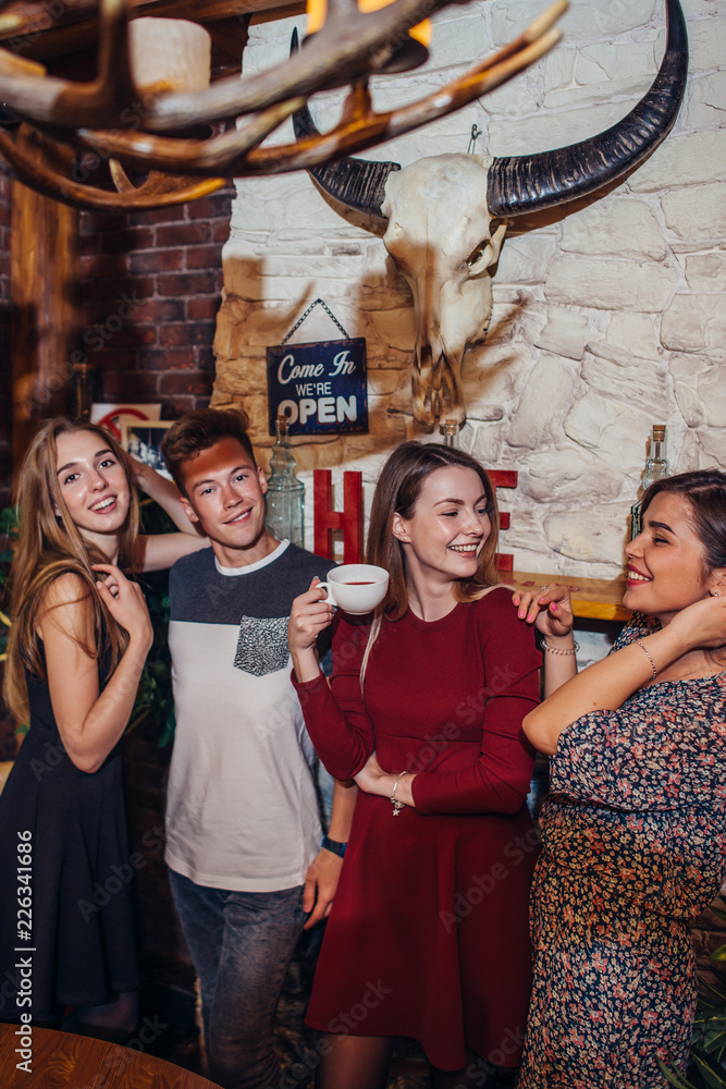 Fototapeta premium Four cool teenagers wearing casual clothes posing for camera in a stylish with hunting lodge interior design.
