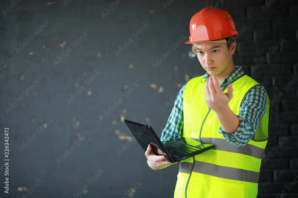 Asian man in protective helmet and construction waistcoat Asian man in protective helmet and construction waistcoat