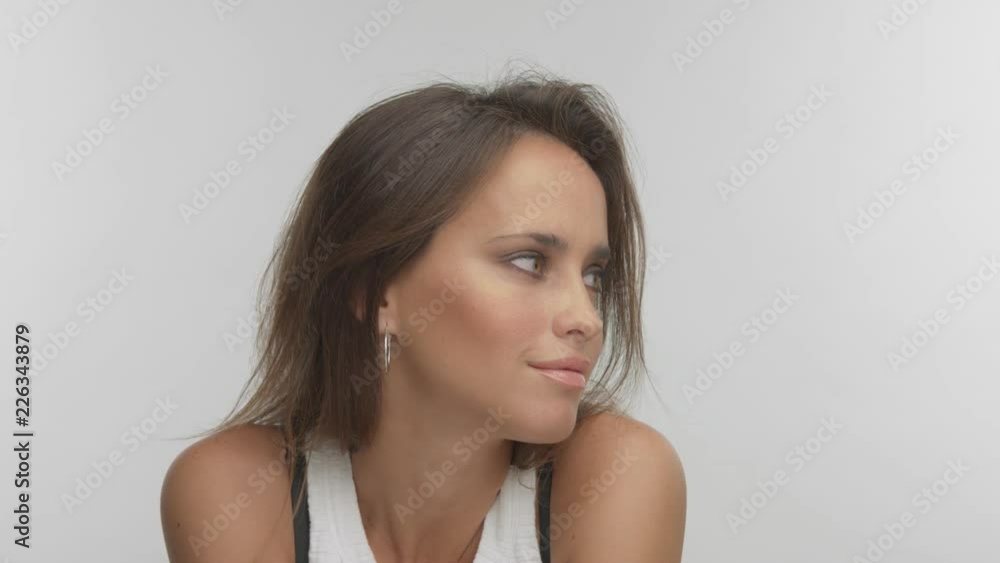 Argentine woman with light blue green eyes poses in studio watching aside and to the camera and smiling Argentine woman with light blue green eyes poses in studio watching aside and to the camera and smiling