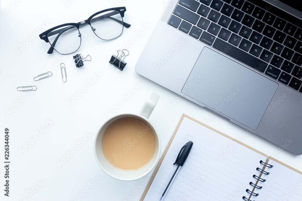Top view workspace ,laptop on white table with coffee cup and office equipment on background Top view workspace ,laptop on white table with coffee cup and office equipment on background