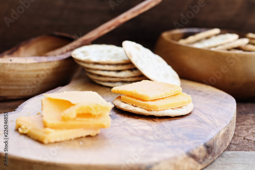 Cheddar cheese and water cracker appetizer over a rustic background.