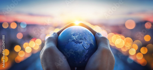 The globe Earth in the hands of man against the night city. Concept on business, politics, ecology and media. Earth day abstract background. Elements of this image furnished by NASA