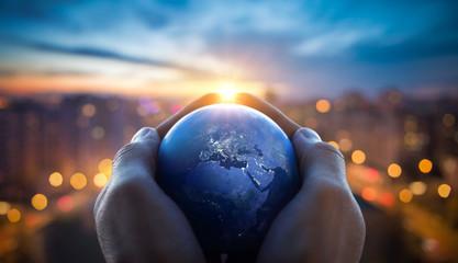 The globe Earth in the hands of man against the night city. Concept on business, politics, ecology and media. Earth day abstract background. Elements of this image furnished by NASA.