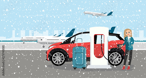 Woman charges an electric car at a charging station for electric vehicles. Rent a car in the airport.  Winter time. Snow.