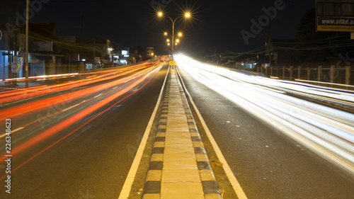 City lights trials of fast moving traffic of cars on the road at night