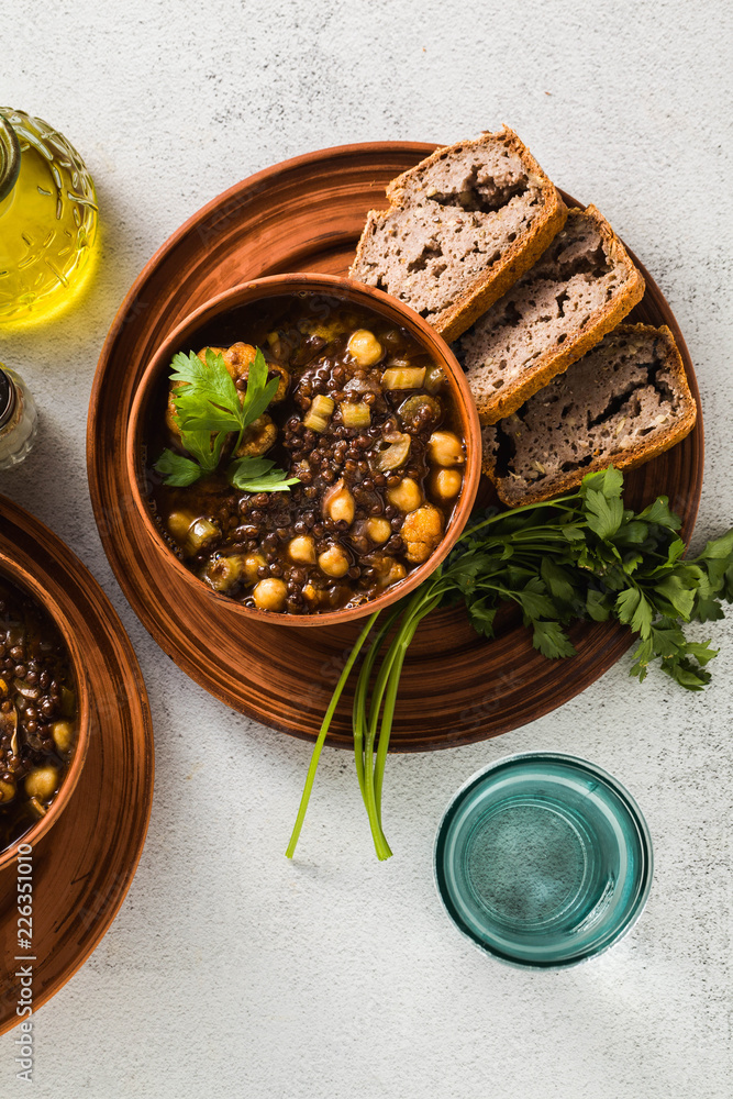 Moroccan black lentil soup with chickpeas and cauliflower in bowls on the table. healthy vegan comfort food with whole wheat bread Moroccan black lentil soup with chickpeas and cauliflower in bowls on the table. healthy vegan comfort food with whole wheat bread