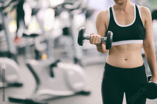 Woman exercising in fitness gym for good health. Athletic young woman exercising equipment at gym, workout in fitness center.