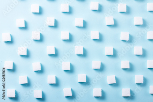 Sugar cubes regular pattern on blue background, flat lay scene