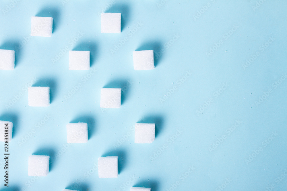 Sugar cubes regulat pattern on blue background, flat lay scene with copy space Sugar cubes regulat pattern on blue background, flat lay scene with copy space