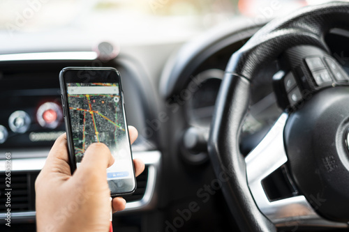 Close up of Man searching destination direction or address on gps or navigator application via mobile smartphone inside a car while driving car (blur on map)