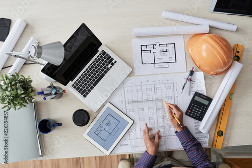 Construction engineer working with various blueprints on his table, view from above