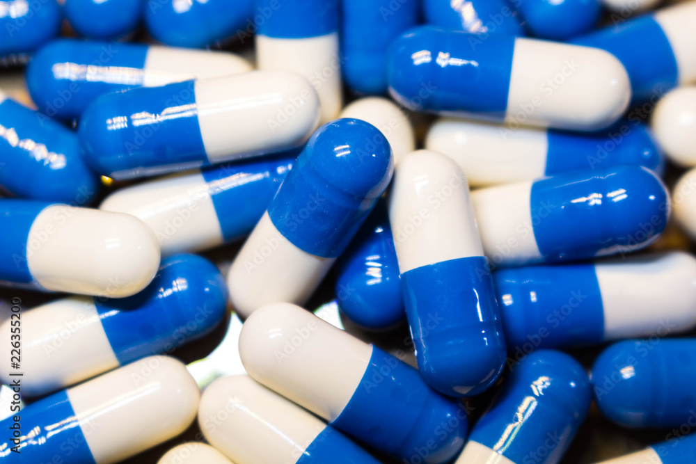 A handful of pills close-up. Capsules medications white and blue. A handful of pills close-up. Capsules medications white and blue.