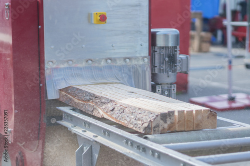 The log, sawn to the board, comes out of the sawmill. Woodworking industry. photo