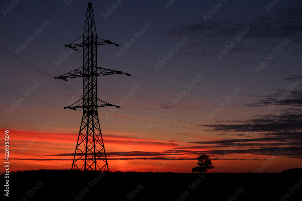 The line of support for electric gears against a sunset.